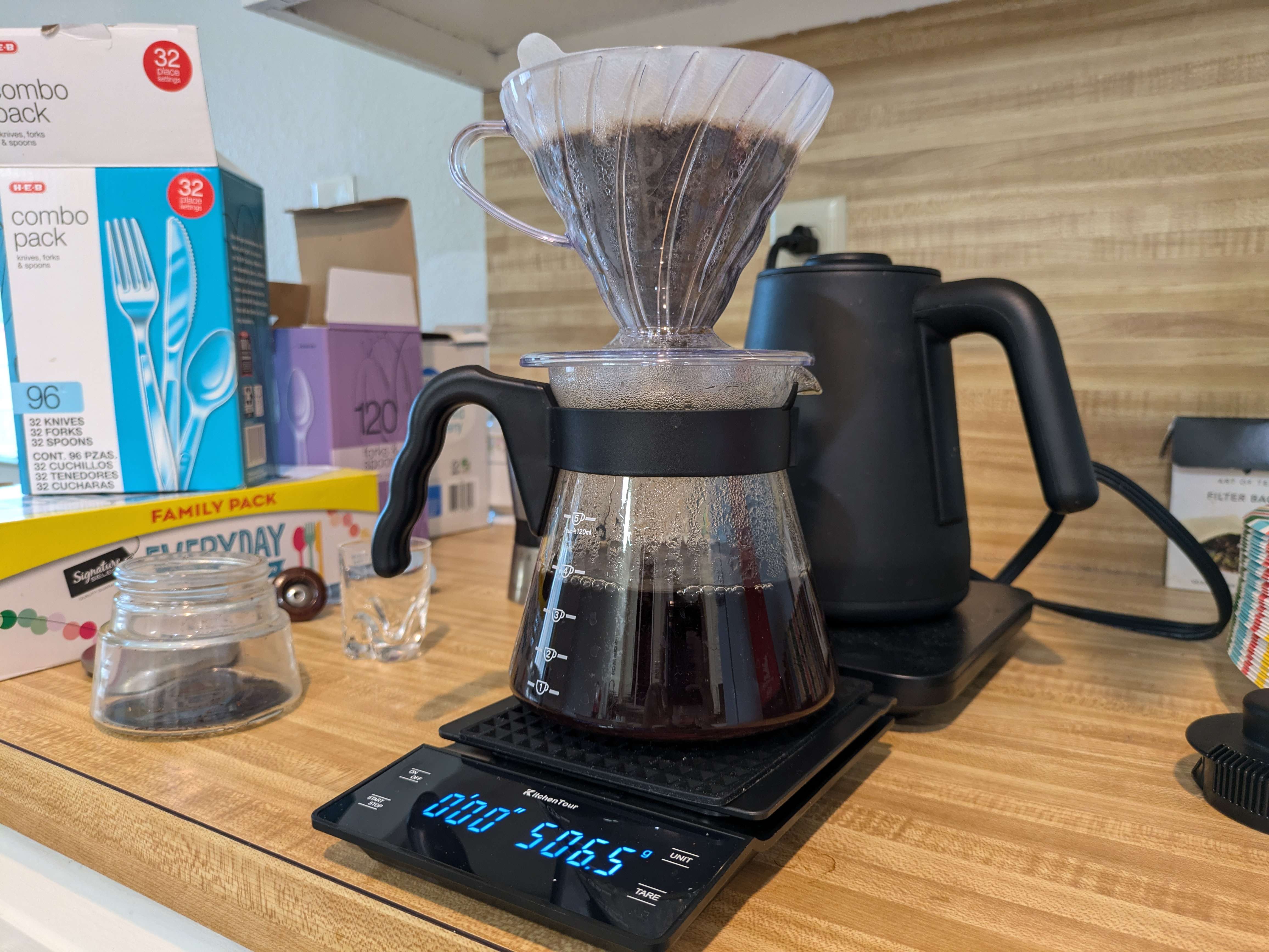 Coffee being brewed in a v60 and beaker,
           sitting on a messy countertop